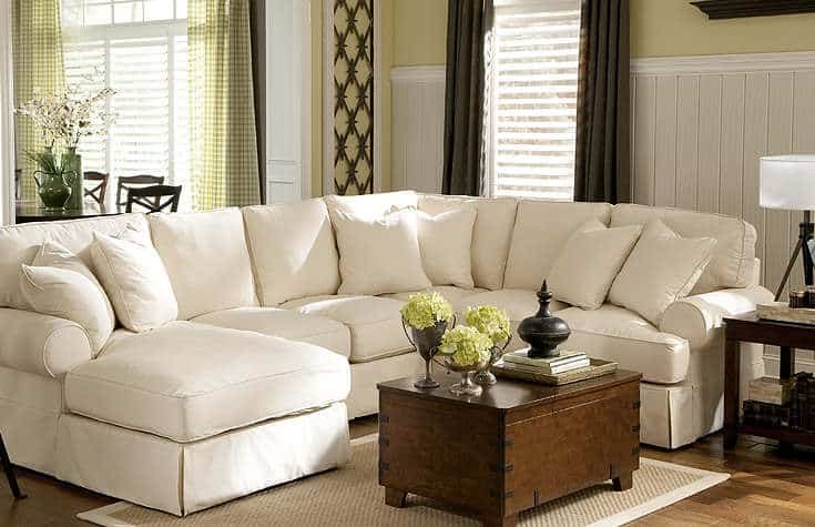 A white sectional sofa with loose back cushions and throw pillows.